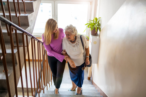 Carer helping an elderly lady walk up stairs