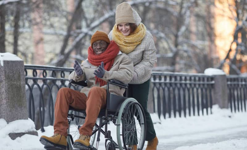 carer pushing wheelchair in snow