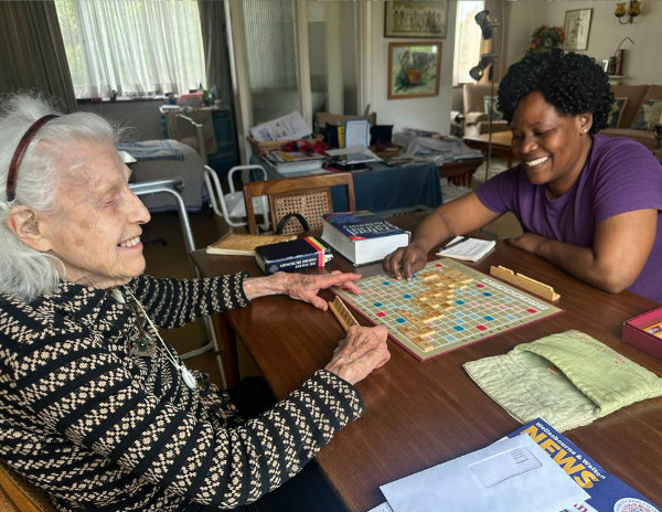 Elderly lady playing scrabble with her carer