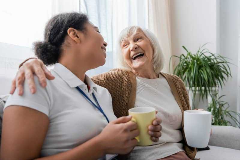Live in Carer and Elderly lady sharing a cup of tea and smiling 