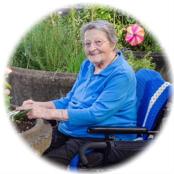 Elderly woman in wheelchair gardening with flowers