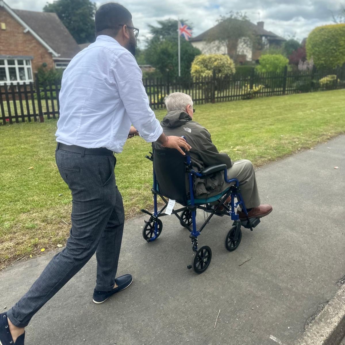 Man assisting elderly gentleman in wheelchair outdoors