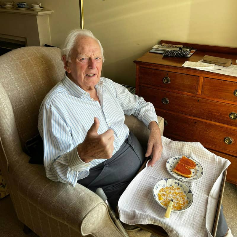 Elderly man eating snack, giving thumbs up