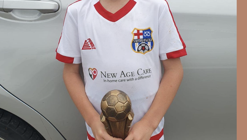 Child in soccer jersey holding a golden soccer ball