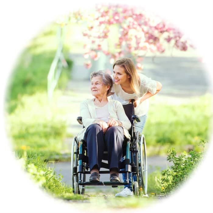 Young woman pushing elderly woman in wheelchair outdoors