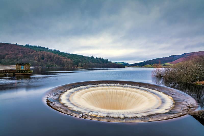 Overflow spillway at reservoir with forested hills