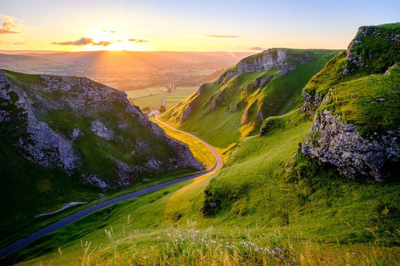 Sunset over winding road in lush green hills