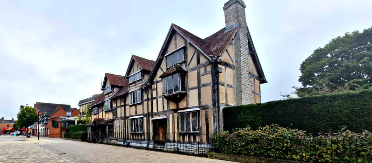 Historic Tudor-style house with hedges on cloudy day