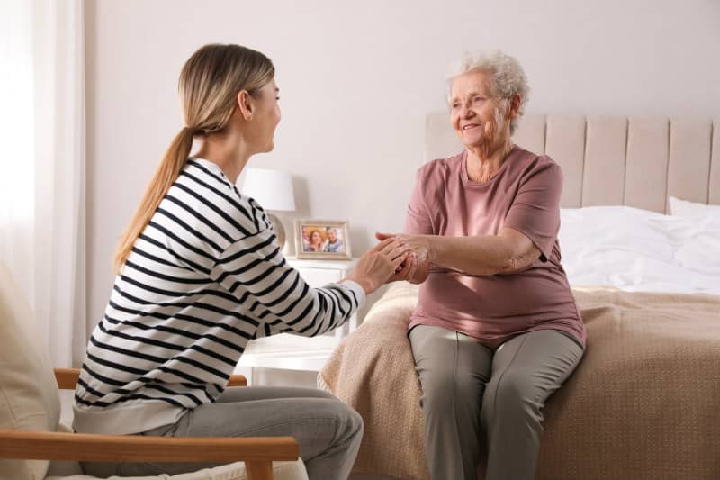 Young woman comforting elderly woman at home