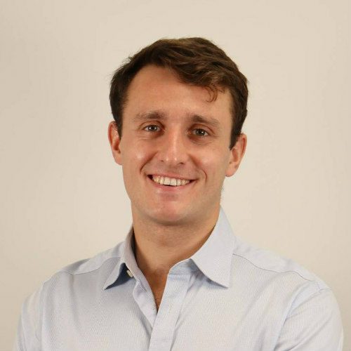 Smiling man in blue shirt against beige background