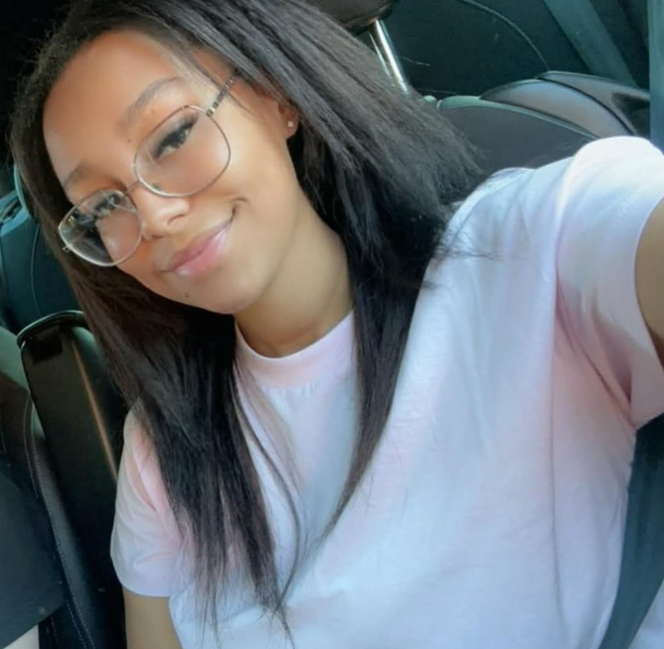 Young woman smiling in car wearing glasses.