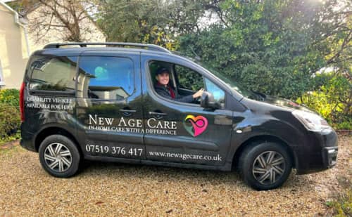 Driver smiling in New Age Care branded vehicle