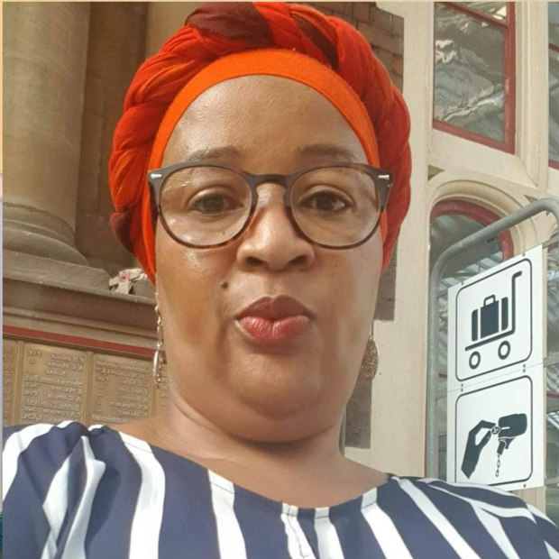 Woman in orange headwrap and striped top with glasses.